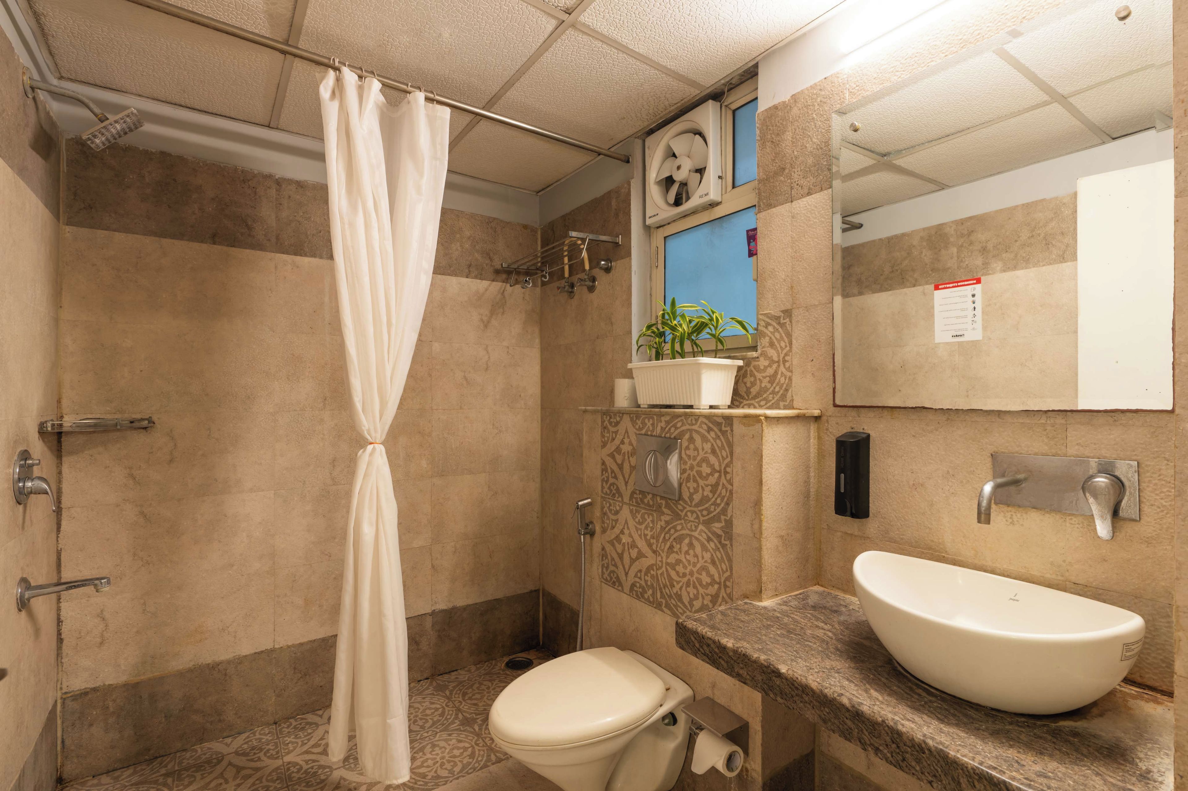 A bathroom with a shower, toilet, sink, and a mirror.