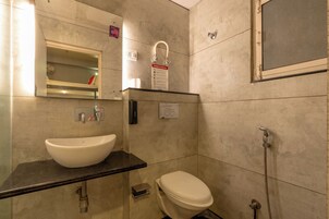 Casa de banho com uma sanita, chuveiro e lavatório branco.