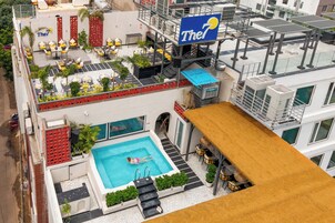Área de piscina no terraço com placa do hotel 'The7', espaço para sentar ao ar livre e uma piscina.