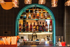 Um balcão com várias garrafas de bebidas e copos nas prateleiras.