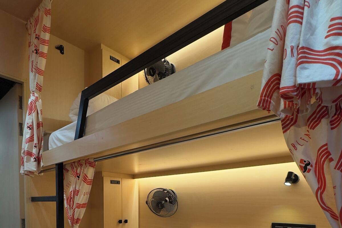 A bunk bed room with a fan, a headboard, and a small cabinet.