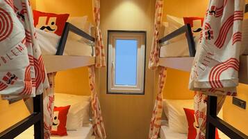 A narrow corridor with bunk beds, a window, and a ceiling vent.