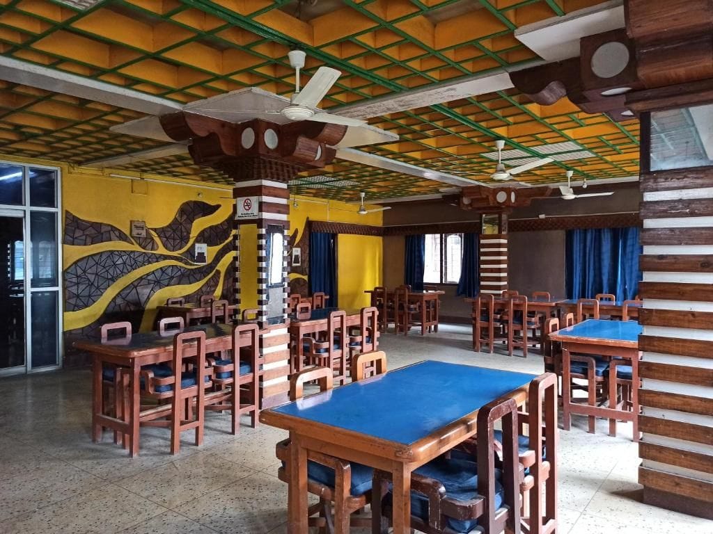 A dining area with multiple tables and chairs, a ceiling with a grid pattern, and a mural on the wall.