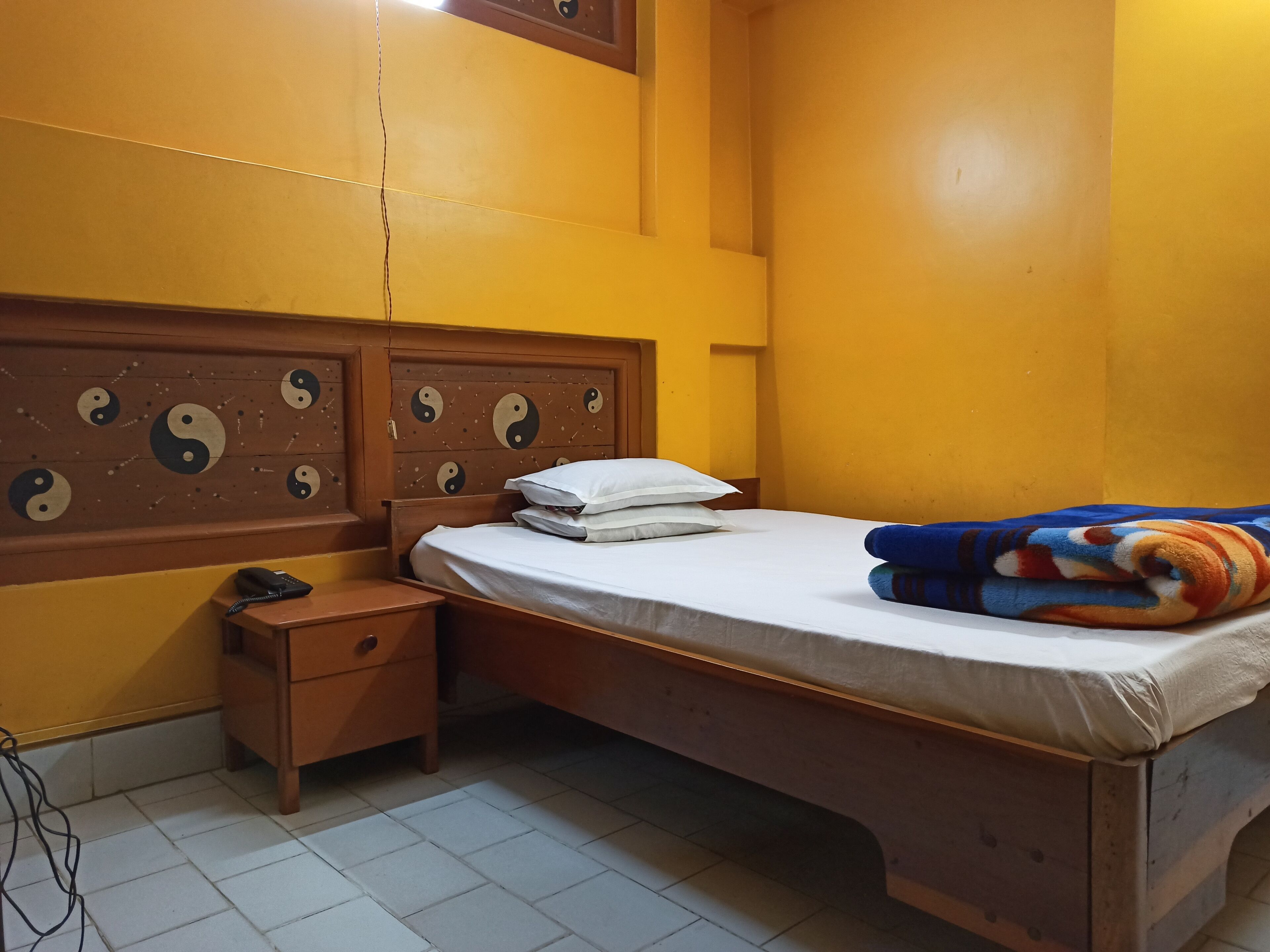 A room with a bed, a nightstand, and a wall with yin-yang symbols.