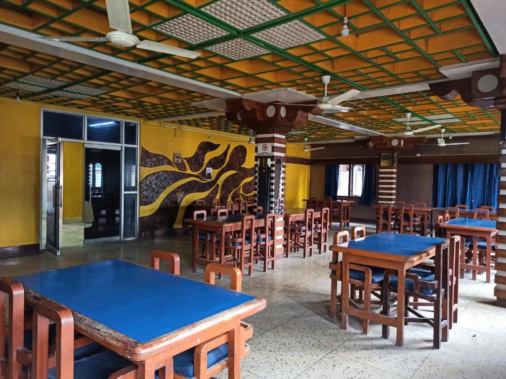 A dining area with multiple tables and chairs, a ceiling fan, and a patterned wall mural.