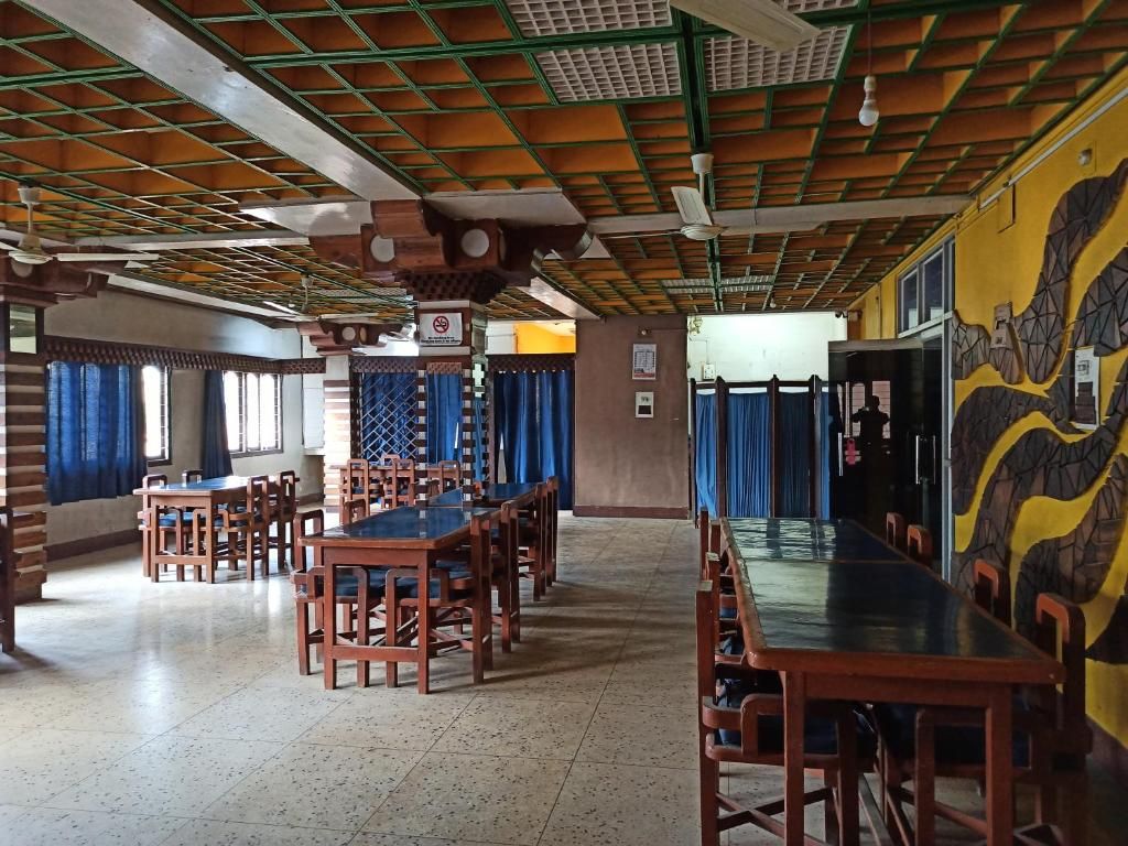 Un comedor con varias mesas y sillas, un techo con diseño de cuadrícula y un mural en la pared.