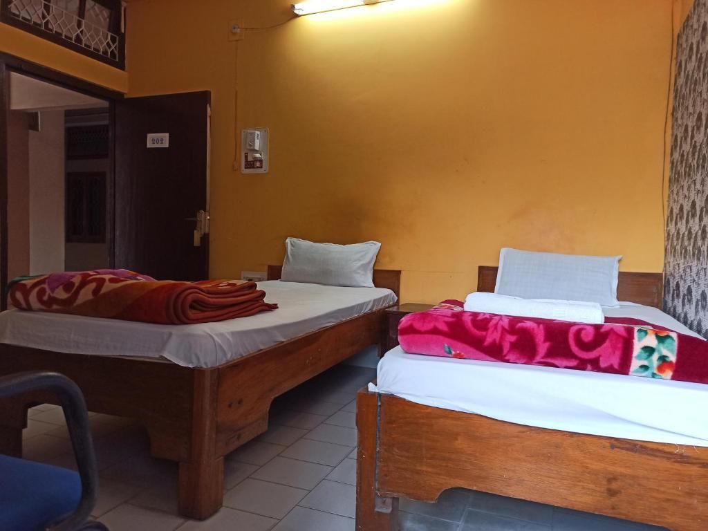 A room with two wooden beds, a chair, and a door.