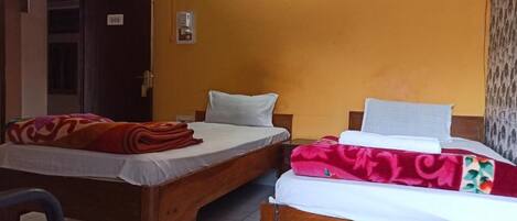 A room with two wooden beds, a chair, and a door.