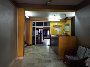 A reception area with a check-in counter, a reception desk, and a seating area with a chair. - Hotel Aane (Papumpare)