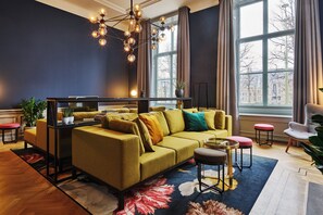 Un salon moderne avec un canapé, une table basse, un lustre et de grandes fenêtres.