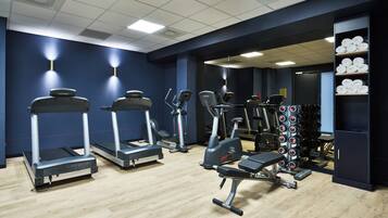 A gym with treadmills, elliptical machines, and weight benches.