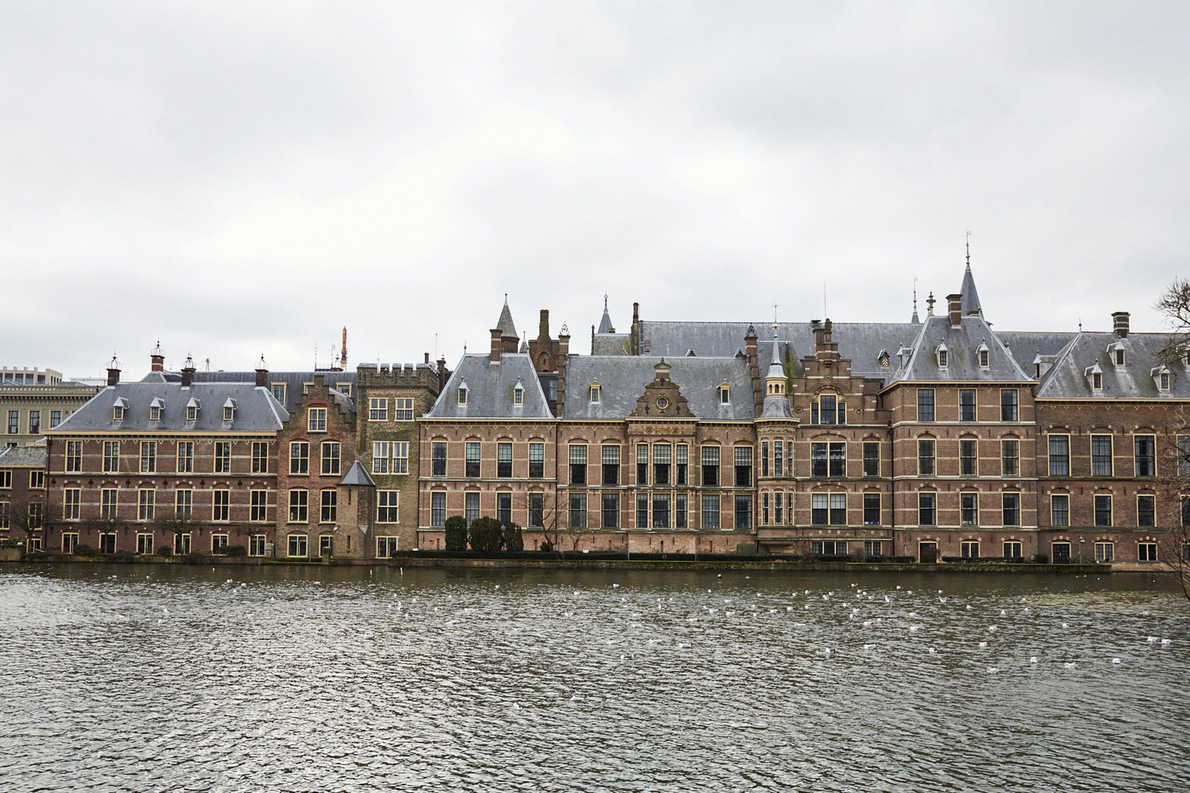 A historic building with multiple windows and a water body in front.