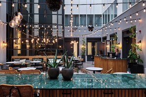 Un espace intérieur moderne doté d’un bar central, de plusieurs coins salon et de luminaires suspendus.