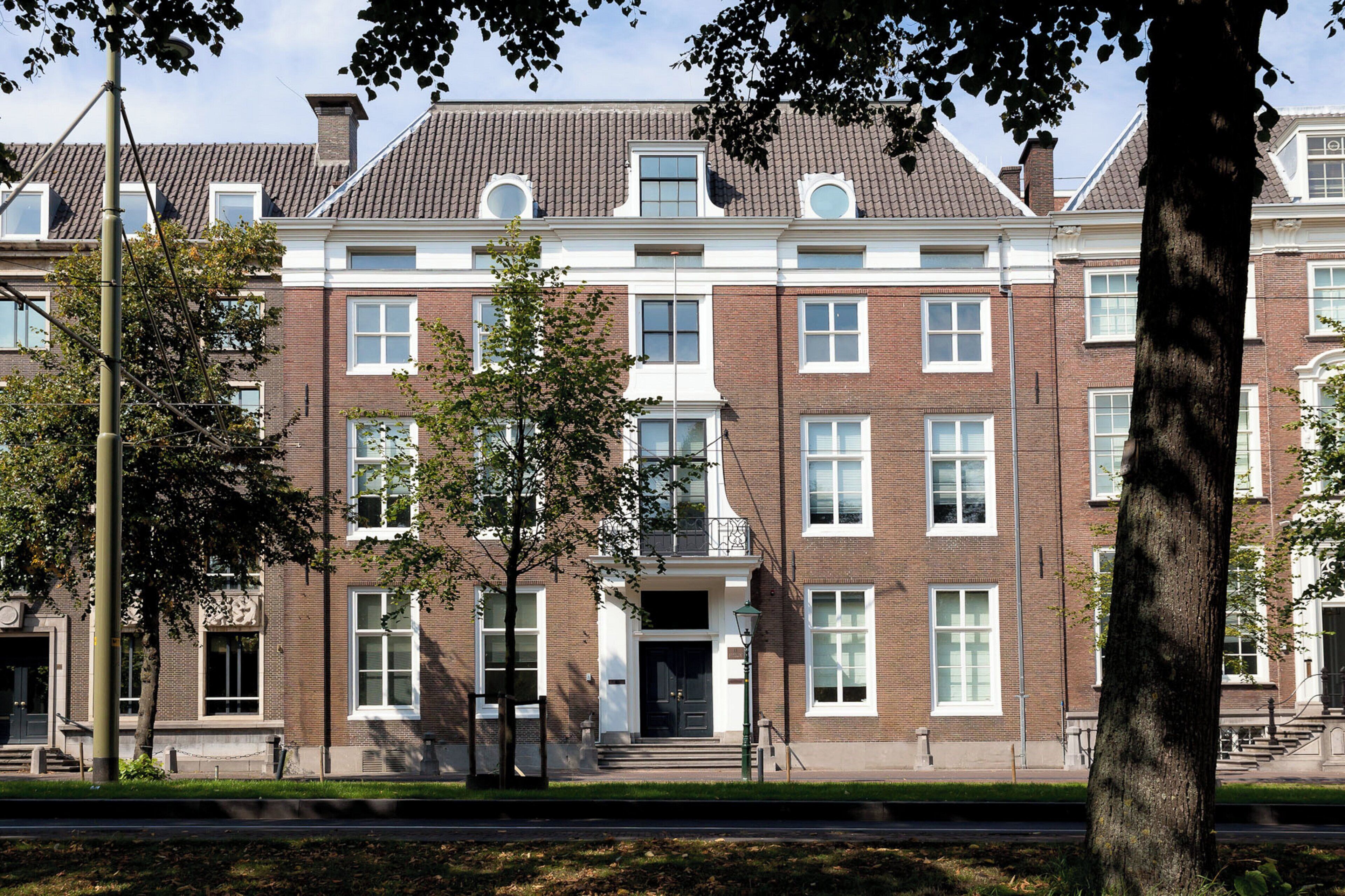 A multi-story brick building with a symmetrical facade, large windows, and a central entrance with steps.