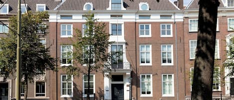 A multi-story brick building with a symmetrical facade, large windows, and a central entrance with steps.