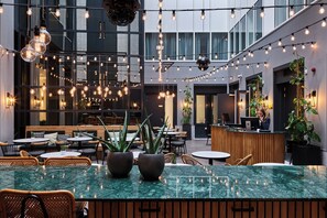 Un espacio interior moderno con una zona de bar central, varios arreglos de asientos y lámparas colgantes.