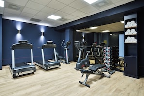 Un gimnasio con cintas de correr, elípticas y bancos de pesas.