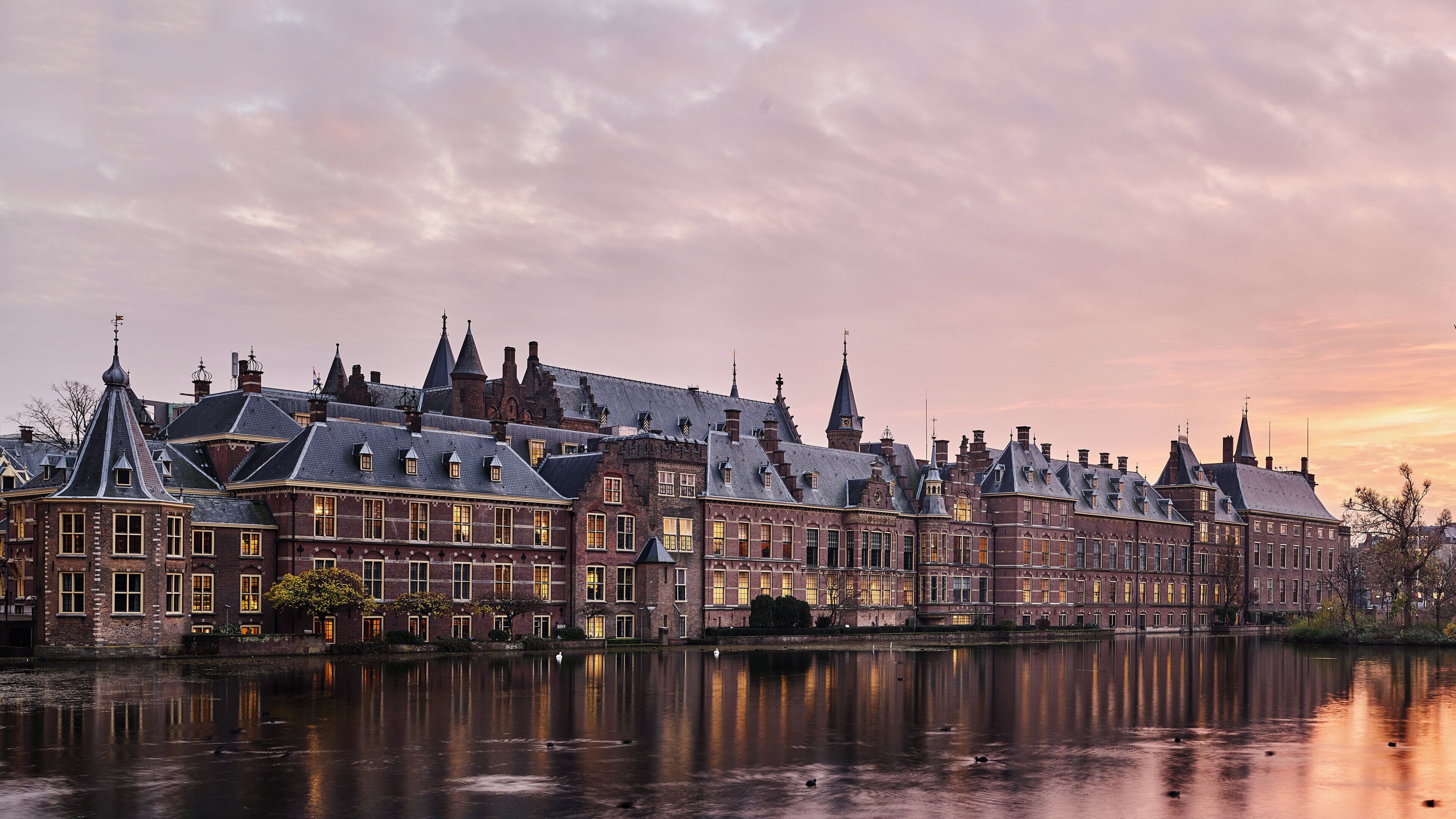 A historic building with multiple gabled roofs and a reflection in the water.