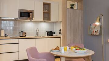 Una cocina moderna con armarios blancos, un microondas y un comedor con mesa lista para el desayuno.