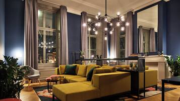 Un salon moderne avec un canapé d’angle, un coin repas et une grande fenêtre agrémentée de rideaux.