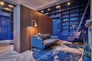 Een moderne woonkamer met een blauwe bank, een houten accentmuur en een blauwe boekenkast.