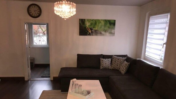 A living room with a dark brown sofa, a white coffee table, and a chandelier. - Fachwerkhaus In Der Altstadt (Lueneburg)