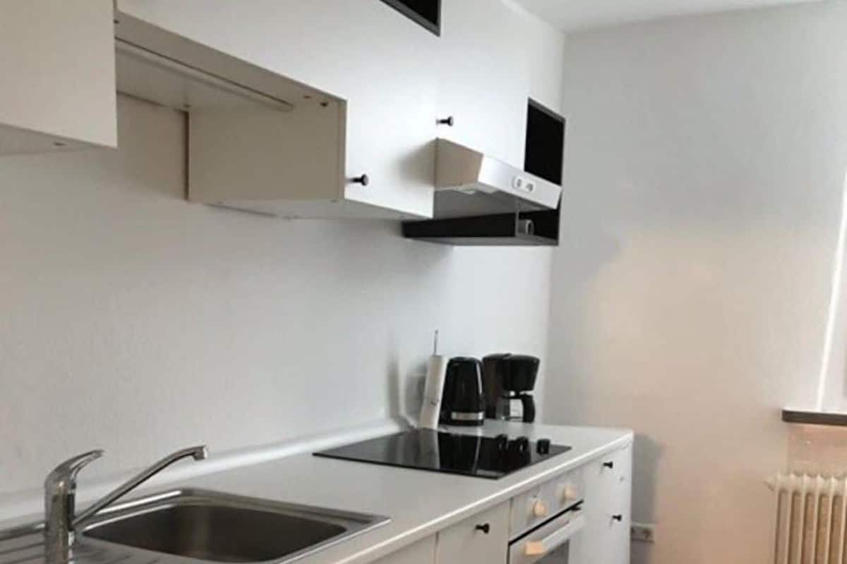 A modern kitchen with white cabinetry, a stainless steel sink, a built-in oven, and a coffee maker.