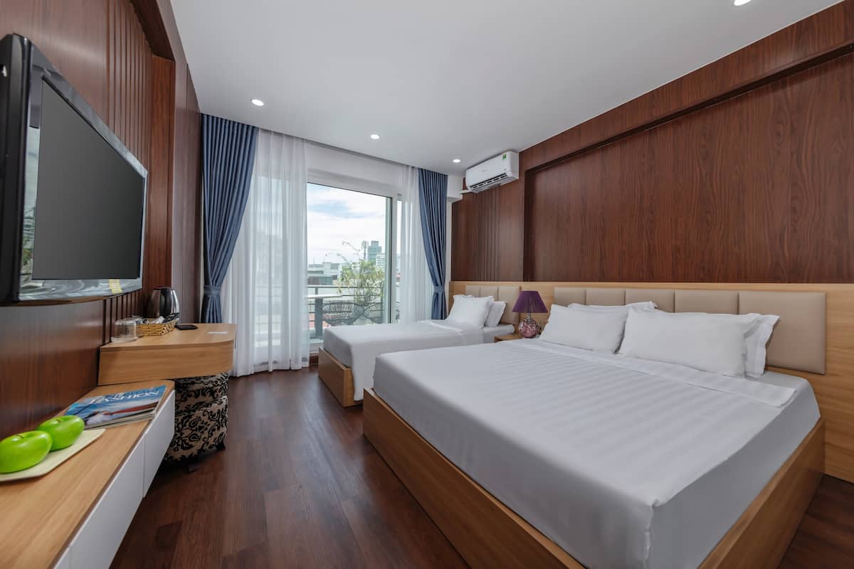 A hotel room with two beds, a TV, a window with curtains, and an air conditioning unit.