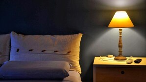 A neatly made bed with a pillow and a bedside table with a lamp, a remote, and a charger. - Cherry Season (Lanciano)