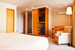 A hotel room with a bed, a wardrobe, a television, a desk, and a chair. - Bourbon Barra da Tijuca Residence (RIO DE JANEIRO)