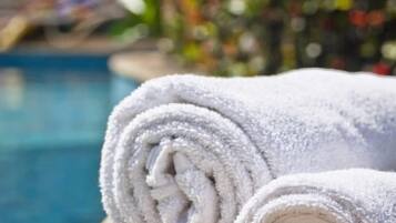 Duas toalhas brancas dobradas sobre uma superfície de madeira perto de uma piscina.