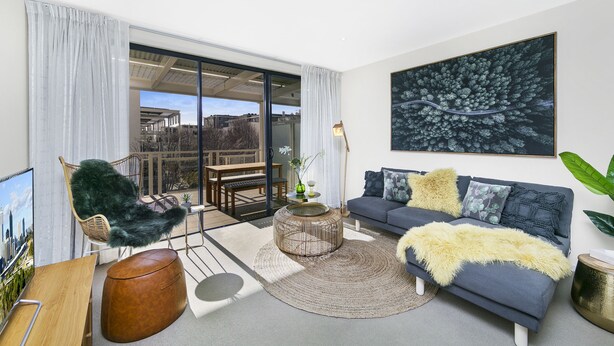 A modern living room with a grey sofa, a round coffee table, and a large window. - Accommodate Canberra - Dawes (Kingston)