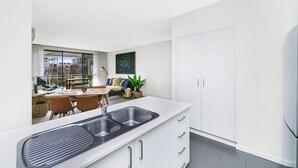 A modern kitchen with a large island, white cabinetry, and a built-in sink. - Accommodate Canberra - Dawes (Kingston)