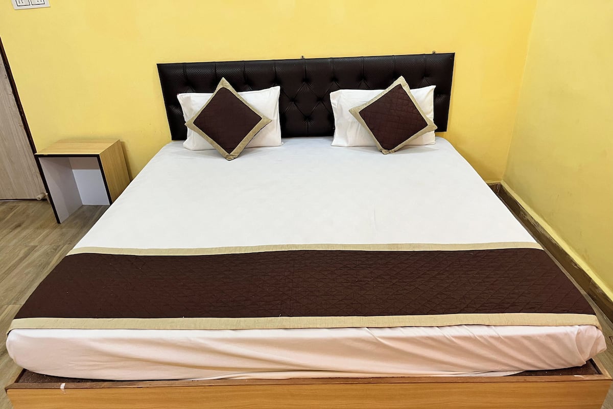 A bed with a brown headboard, white bedding, and two brown pillows.