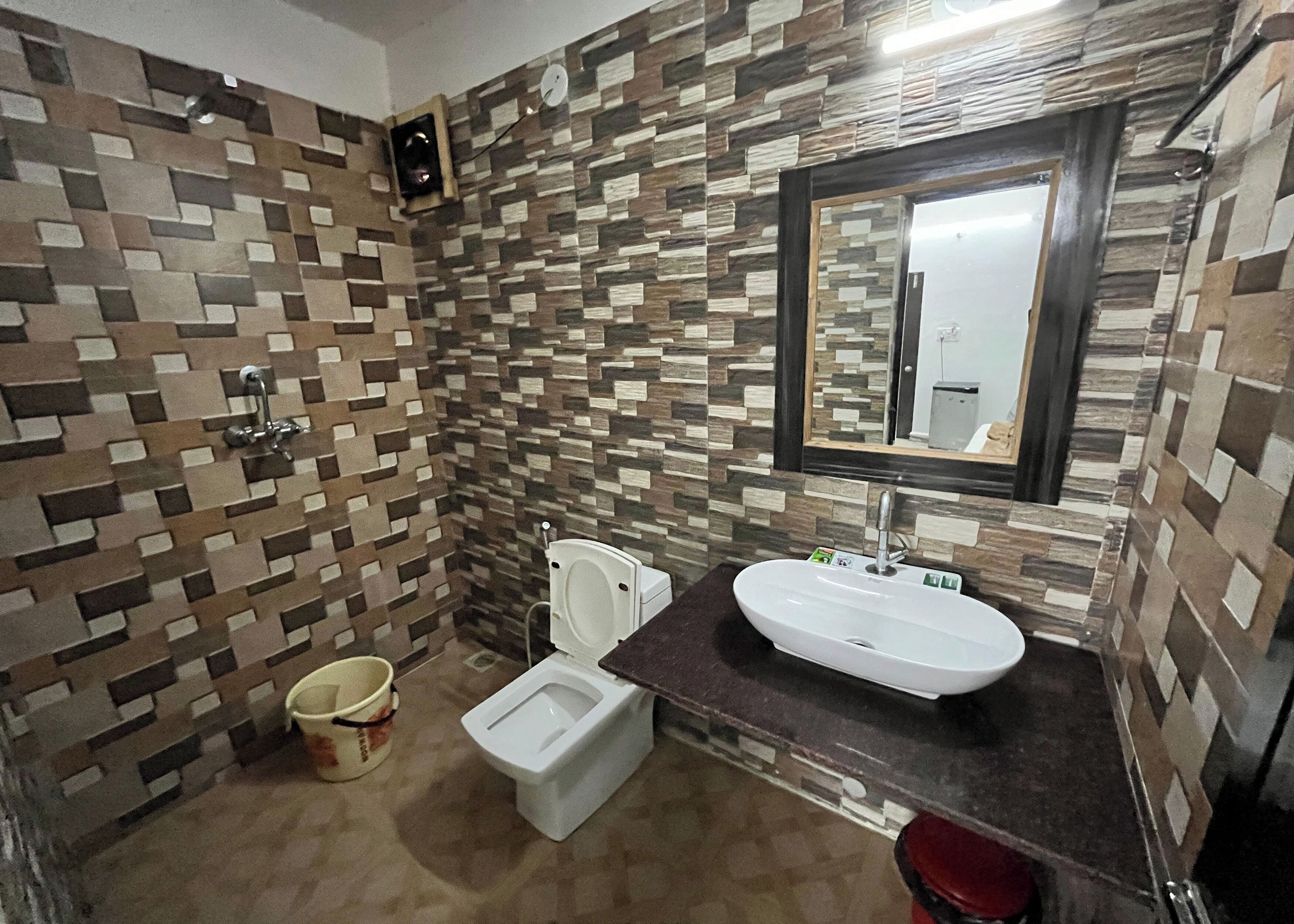 A bathroom with a tiled wall, a toilet, a sink, and a mirror.