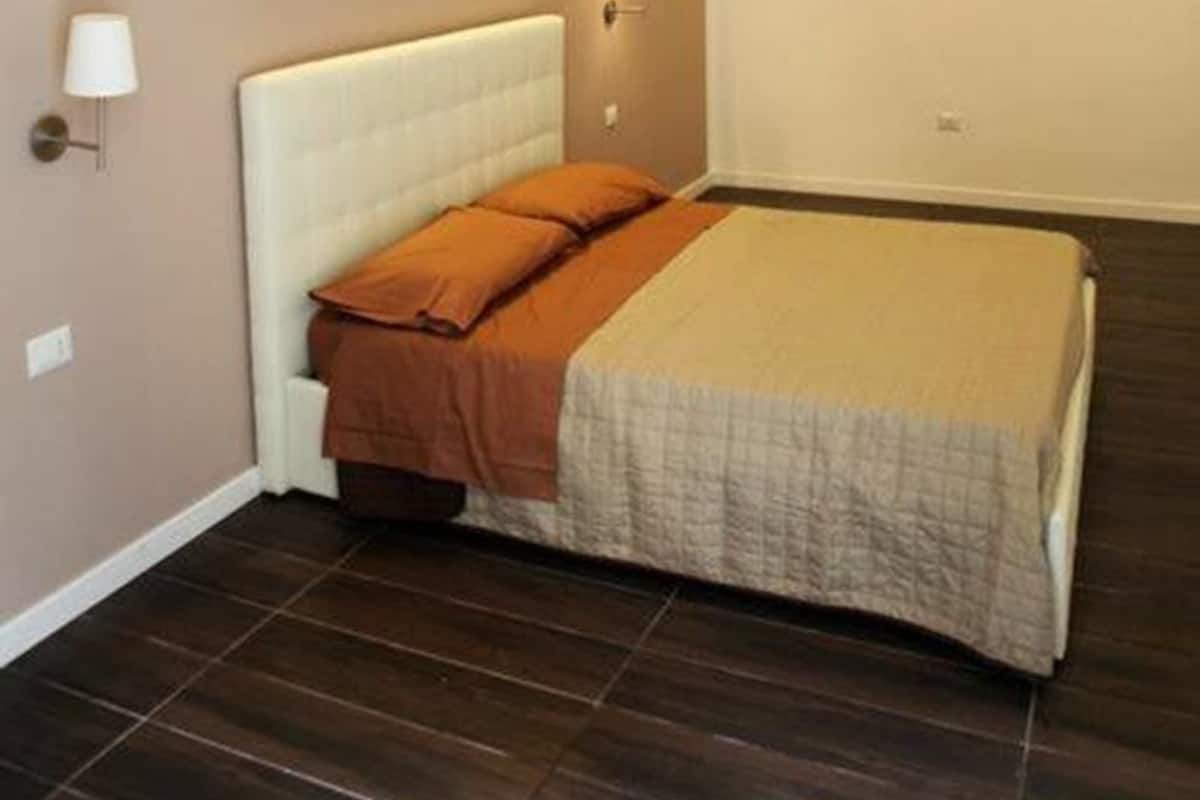 A modern bedroom with a large bed, recessed wall lighting, and a minimalist design.