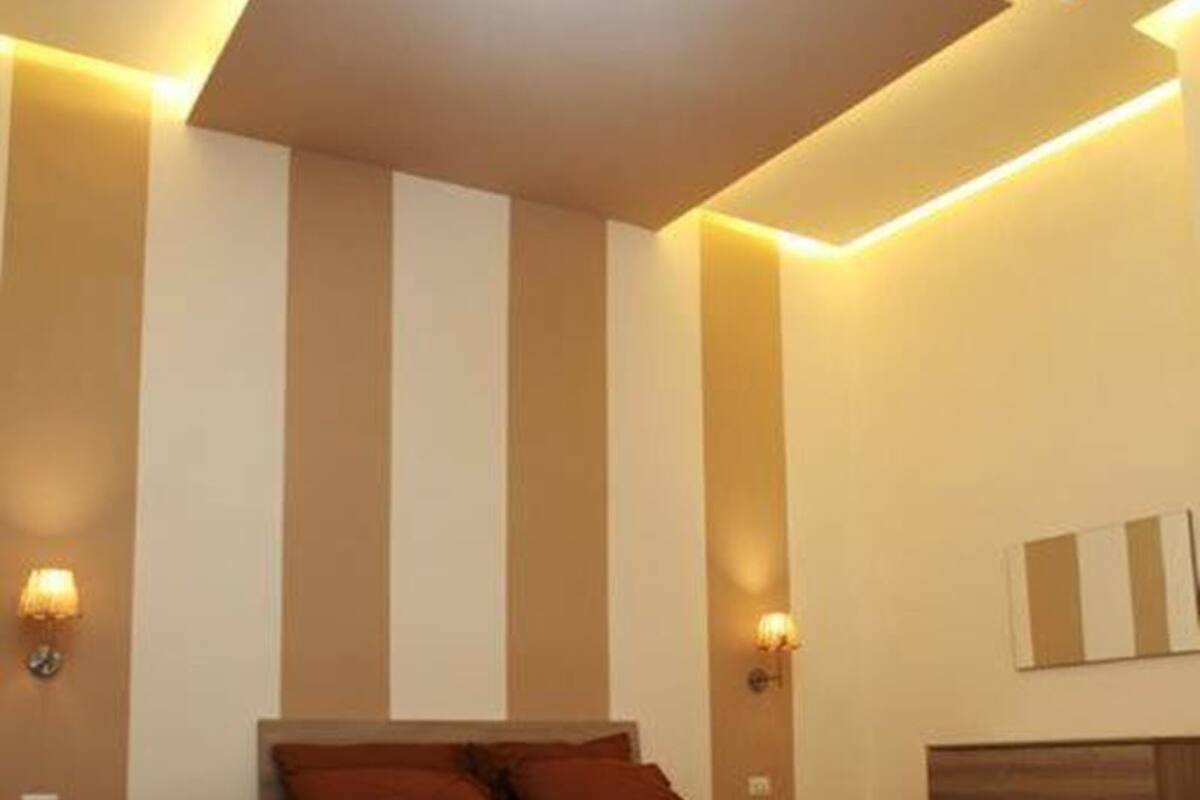 A modern bedroom with a bed, bedside tables, and wall-mounted lighting.