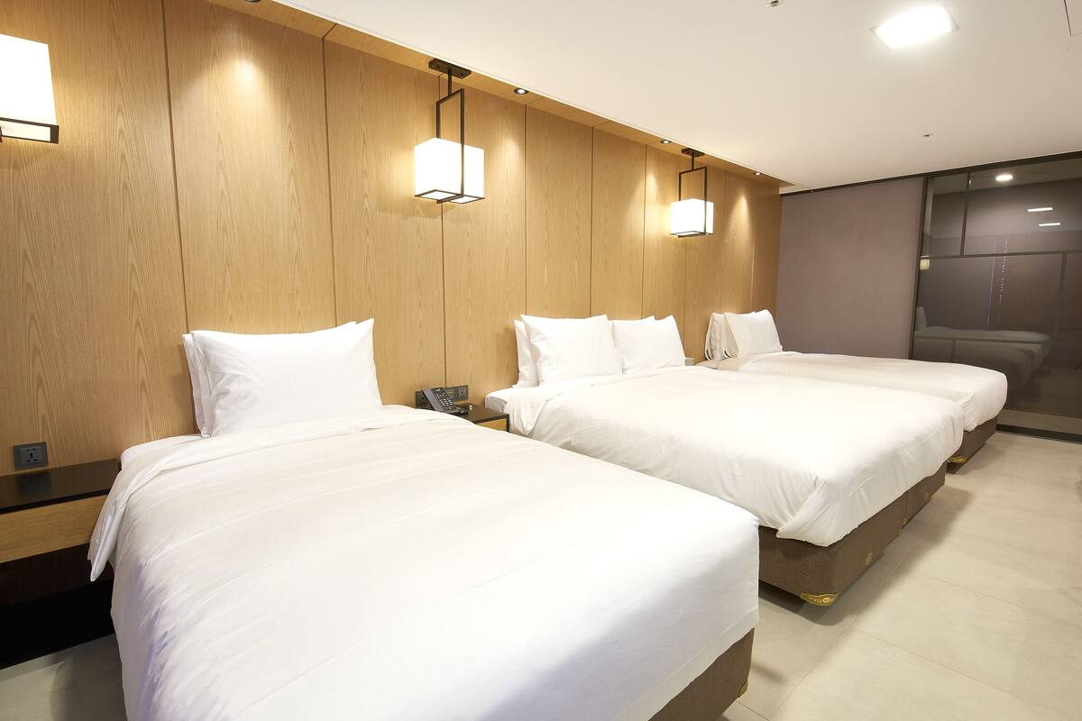 A hotel room with two beds, wooden paneling on the walls, and a modern design.