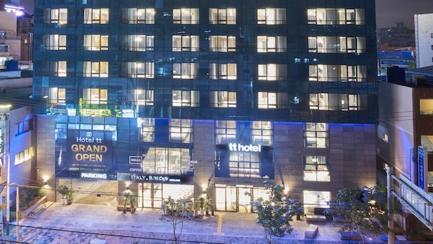 Ein Hochhaus-Hotel mit mehreren Etagen, beleuchteten Fenstern und einem gut sichtbaren Schild mit der Aufschrift 'Hotel Grand Open' am Eingang.