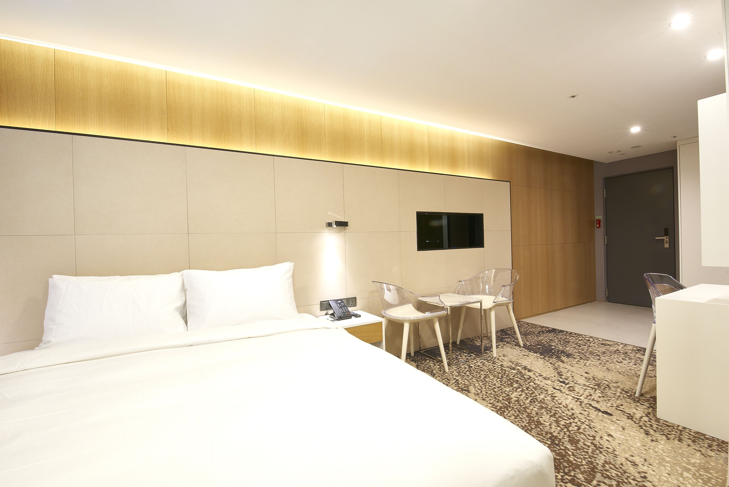 Ein modernes Hotelzimmer mit einem großen Bett, einem Schreibtisch mit Stuhl, einem Flachbildfernseher und einem kleinen Tisch mit Sitzgelegenheit.