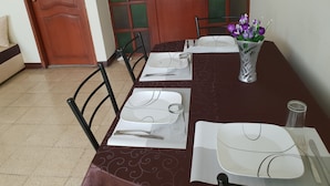 A dining area with a long table set for four, including place settings, cutlery, and a vase with flowers. - Guayaquil In Love (Guayaquil)