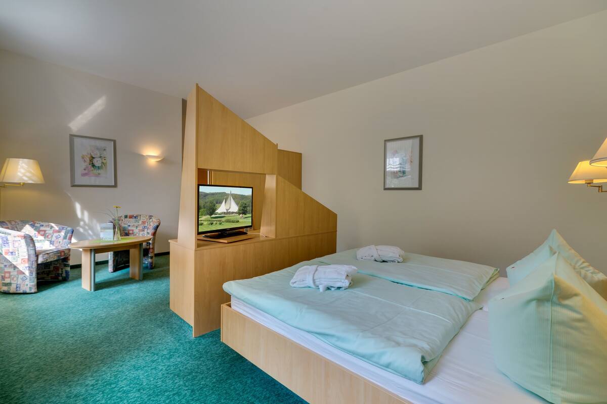 A hotel room with a bed, a TV, a desk, and a chair.