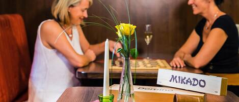 Una mesa de madera con una tarjeta de identificación, dados y un florero con flores amarillas.