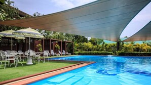 A swimming pool with a shaded area, lounge chairs, and a small garden. - Kwanruen Resort (Nakhon Ratchasima)