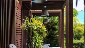 A covered outdoor seating area with white lounge chairs and a pergola structure. - Kwanruen Resort (Nakhon Ratchasima)