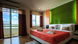 A hotel room with a large bed, a green accent wall, and a view of the outdoors. - Kwanruen Resort (Nakhon Ratchasima)