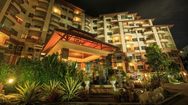 A multi-story hotel with a central atrium, outdoor seating area, and lush landscaping. - Kwanruen Resort (Nakhon Ratchasima)