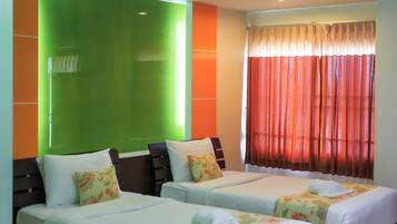 Quarto de hotel com duas camas, uma mesa de jantar e uma parede verde decorativa.