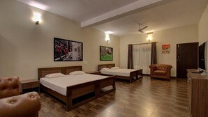 A hotel room with two wooden beds, a leather armchair, a TV, and artwork on the walls. - Forestdale Coorg (Virajpet)