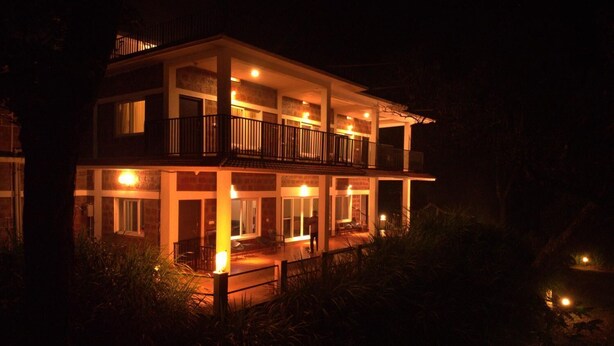 A two-story building with a balcony on the upper floor, surrounded by vegetation. - Forestdale Coorg (Virajpet)